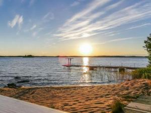 a beach with the sun setting on the water at Holiday Home Hästöskata b by Interhome in Kruunupyy