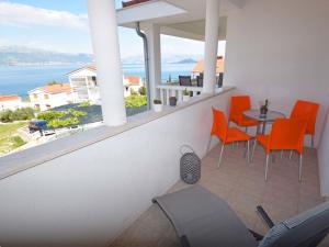 einen Balkon mit orangefarbenen Stühlen und einem Tisch mit Aussicht in der Unterkunft Apartment Anđa-4 by Interhome in Trogir