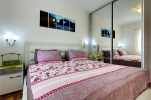 a bedroom with a large bed with pink sheets and mirrors at Varja 2 Apartment in Sveti Stefan
