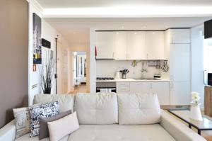 uma sala de estar com um sofá branco e uma cozinha em Tejo Blue & Bright - Checkinhome em Lisboa