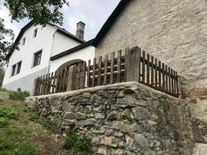 einen Zaun an einer Steinmauer vor einem Haus in der Unterkunft Statek u Potoka in Vimperk