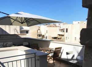 a patio with a table and an umbrella on a balcony at B&b Il Tufo in Favignana