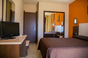 um quarto de hotel com uma cama e uma televisão de ecrã plano em Hotel La Nava em Iznalloz