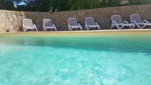un grupo de sillas sentadas junto a una piscina en Résidence Saint Michel, en LʼÎle-Rousse