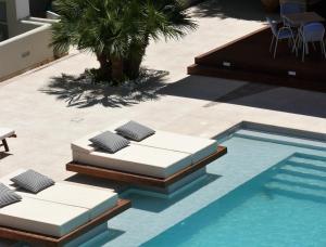 a pool with two beds next to a palm tree at Danae Hotel in Egina