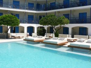 a swimming pool with lounge chairs and a building at Danae Hotel in Egina