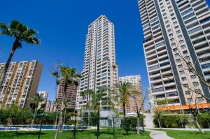a park with palm trees and tall buildings at Apartamentos con terraza Torre D'Oboe by Renthas in Benidorm