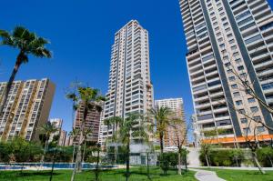 een park met palmbomen en hoge gebouwen bij Apartamentos con terraza Torre D'Oboe by Renthas in Benidorm