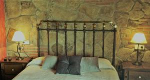 a bedroom with a bed with two lamps and a stone wall at El Cerrillo 1 in San Martín del Pimpollar