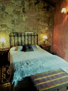 1 dormitorio con 1 cama en una pared de piedra en El Cerrillo 1, en San Martín del Pimpollar