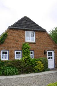 a red brick house with white windows and bushes at Schoppstuv in Tümlauer Koog