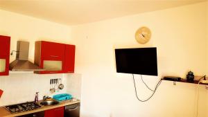 a kitchen with red cabinets and a tv on the wall at Apartments Niko Metajna, island Pag in Metajna