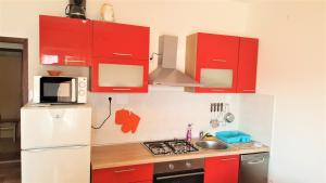 a kitchen with red cabinets and a white refrigerator at Apartments Niko Metajna, island Pag in Metajna