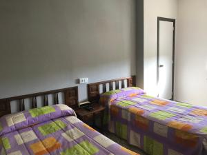 a bedroom with two beds and a mirror in it at Hostal San Miguel in León
