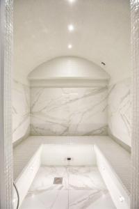 a bathroom with a shower with white marble walls at Apartment "House 213" in Voronezh