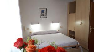 a bedroom with a bed with red roses on a table at Hotel Villa Dina in Lido di Jesolo