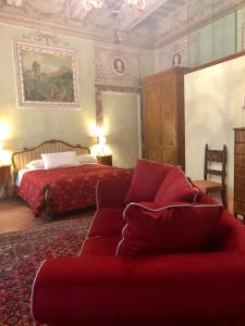 een slaapkamer met een bed en een rode bank bij B&B Il Gianduia in Lucignano