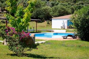 a swimming pool in a yard with a bench and flowers at Hotel Baia Cea in Bari Sardo