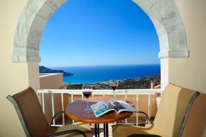 a table with two glasses of wine on a balcony at Stefanos Village Hotel in Plakias