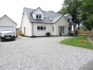 a house with a gravel driveway in front of it at The Willows in Beauly