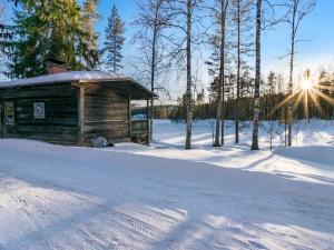 una cabaña de madera en la nieve con el sol en el fondo en Holiday Home Saarijärvi by Interhome, en Sipilä