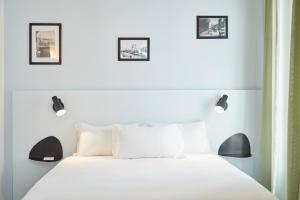 a bedroom with a white bed with two pictures on the wall at Hôtel Maison Saint Louis - Vieux Port in Marseille