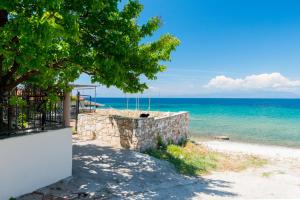 a stone wall on the beach with the ocean at Ioanna Studios in Skala Kallirachis