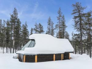 a building covered in snow with trees in the background at Holiday Home Arctic light hut by Interhome in Kakslauttanen