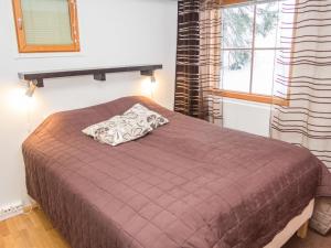 a bedroom with a bed with a brown blanket and a window at Holiday Home Karhunvartijan linna a3 by Interhome in Ruka +5 photos