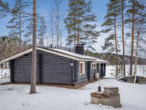 uma pequena cabana de madeira na neve com árvores em Holiday Home Aurinkoniemi by Interhome em Anttola