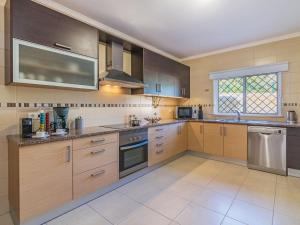 a large kitchen with wooden cabinets and stainless steel appliances at Holiday Home Vila Caravela by Interhome in Estevais