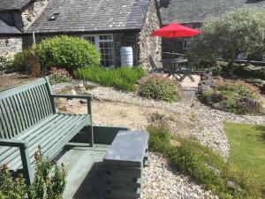 a bench with a red umbrella in a garden at Garth Engan Private Self Contained B&B with Garden Area in Llanbedr