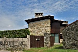 una casa de piedra con chimenea y valla en casa da pedra, en Tomiño