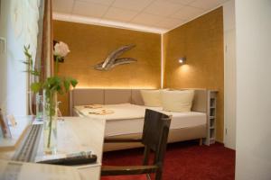 a small room with a bed and a desk and a table at Flair-Waldhotel Mellestollen in Saalfeld