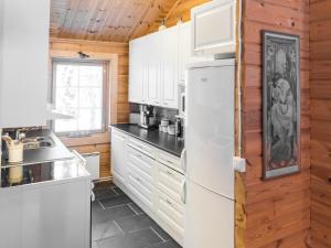 a kitchen with white appliances and wooden walls at Holiday Home Oivangin siesta by Interhome in Nissi +12 photos