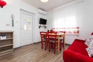 a living room with a red couch and a table and chairs at Apartments Ana Baska in Baška