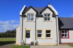 a white house with yellow trim at Giant's Causeway Holiday Cottages in Bushmills