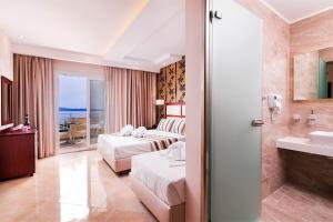 a hotel room with two beds and a bathroom at Hotel Diamond in Limenaria