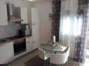 una cocina con una mesa pequeña y una cocina con armarios blancos. en New apartment Dany with parking for two, en Split