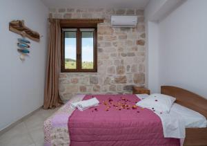 Villa windmill Near Shipwreck Beach by "elite" في Volímai: غرفة نوم بها سرير وردي عليه زهور