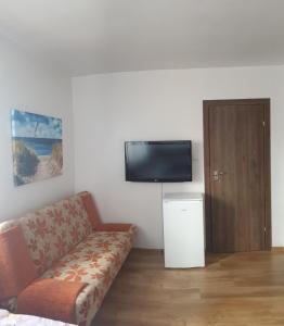 a living room with a couch and a flat screen tv at Pokoje Gościnne Pryzmat in Władysławowo