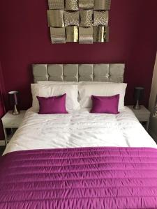 een wit bed met paarse lakens en 2 paarse kussens bij The Avenues in Chelmsford