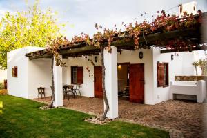 a white house with a pergola with flowers on it at Vineyard Cottage at Bosman Wines in Wellington