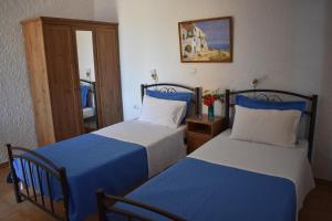 a bedroom with two beds with blue and white sheets at Eriketi Studios in Agia Marina Aegina