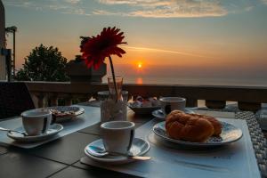 a table with plates of food on a table with the sunset at B&B Villa Belvedere in Vasto