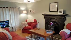 a living room with a fireplace and red chairs at Bay View House in Liscannor