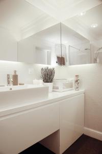 W białej łazience znajduje się umywalka i lustro. w obiekcie Biały apartament z tarasem w Playa Baltis w mieście Międzyzdroje