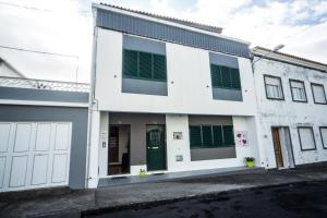 een wit gebouw met groene luiken erop bij AL - Apartamento Bairros Novos 24 in Ponta Delgada