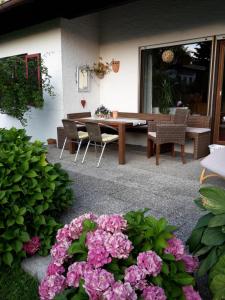 un patio con mesa, sillas y flores rosas en Ferienhaus Irger, en Marquartstein