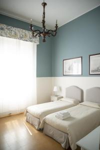 2 camas en un dormitorio con paredes azules y una lámpara de araña en La Casa Di Anna B&B en Reggio Calabria